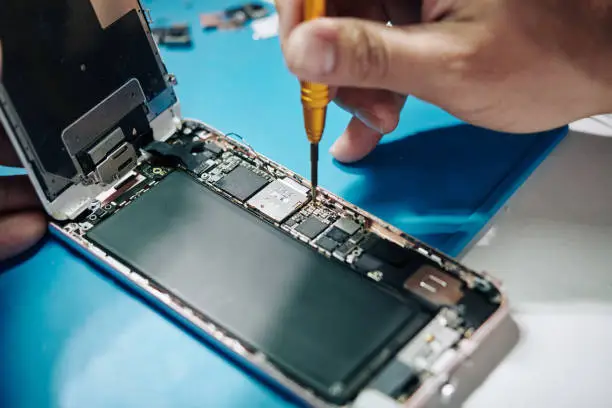 Repairman man securing a screw after checking SIM card tray of smartphone with removed screen