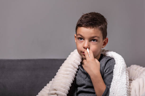 istock Kid is having flu and he is using nasal spray to help himself. Boy using nasal spray. Nasal spray to help a cold. Sick with a rhinitis little boy dripping nose. Kid applies nasal spray 1183925423