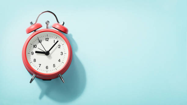 istock Red alarm clock with shadow lying on blue background. View from above. 1183927492