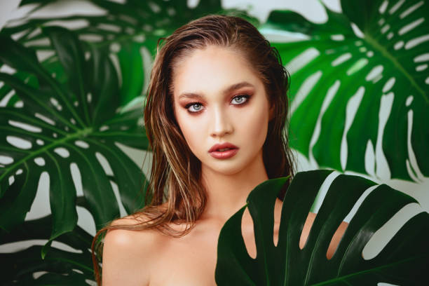 istock young attractive woman posing with a fresh green leaf 1183929100