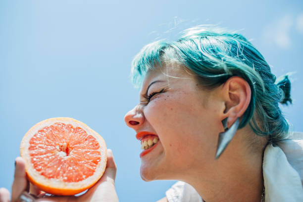istock Woman with blue hair eating oranges 1183929511