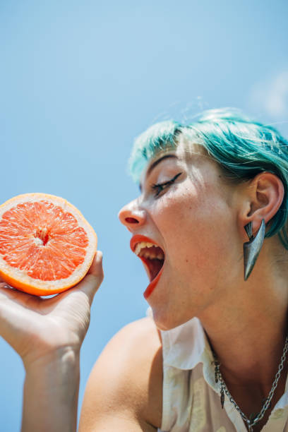 istock Woman with blue hair eating oranges 1183929552
