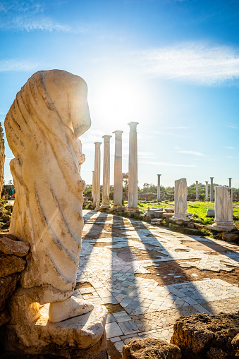 Marble statue under the sun rays and ancient columns at Salamis, Greek and Roman archaeological site, Famagusta, North Cyprus