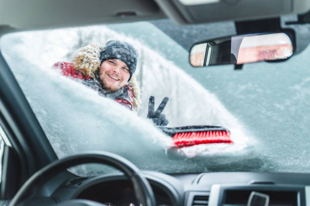istock cleaning car after snow storm smiling man with brush view from inside interior 1183933404