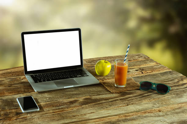 istock Blank laptop on a wooden table outdoors, mock up 1183933560
