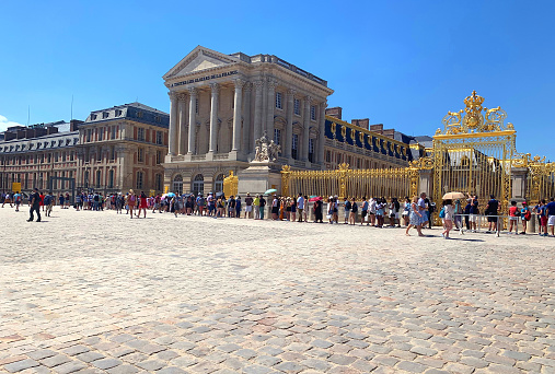 Versailles / France - July 6, 2019: Extremely huge queue of tourists in Palace of Versailles waiting for their tickets in Paris, France, summer time. Very famous tourist attraction in Europe