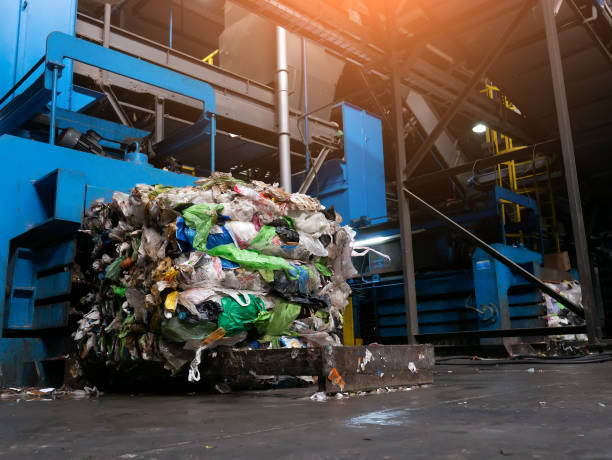 istock Modern waste sorting and recycling plant, hydraulic press makes wired bale from pressed PET bottles for processing and reuse of plastic. Concept of defence of environment by materials recycle. 1183935508