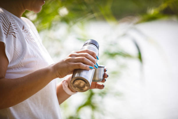 istock Woman pouring coffee while standing by river 1183936131