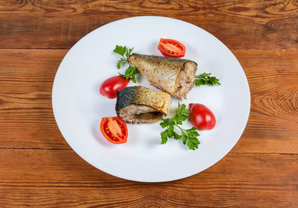 istock Baked mackerel slices, greens, tomatoes on dish on rustic table 1183936196