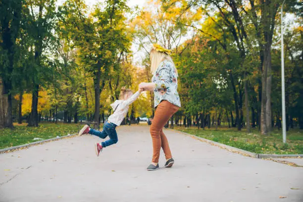 mather with little toddle daughter playing in autumn city public park activities