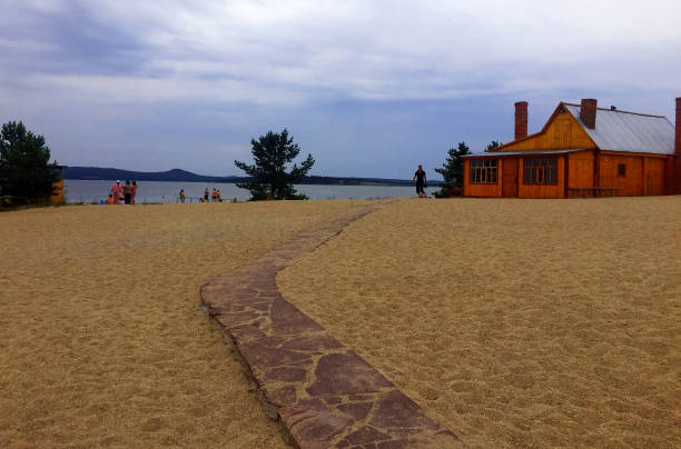 Zerenda / Kazakhstan - June 15, 2019: Stoned pathway in the middle of the sand leading to wooden summer house in the beach. Touristic location.