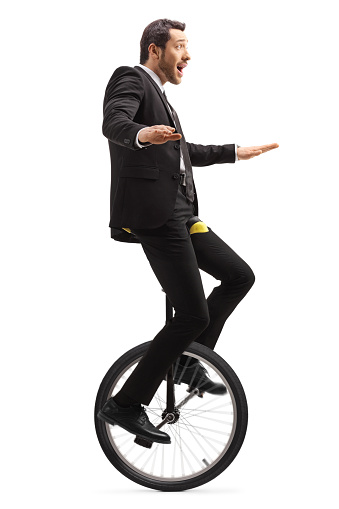 Full length shot of a suprised businessman riding a mono-cycle isolated on white background