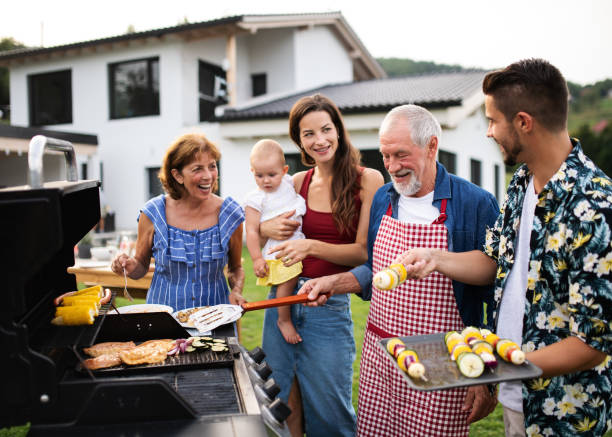 Portrait of multigeneration family outdoors on garden barbecue, grilling. Portrait of multigeneration family outdoors on garden barbecue, grilling and talking. barbecue social gathering photos stock pictures, royalty-free photos & images