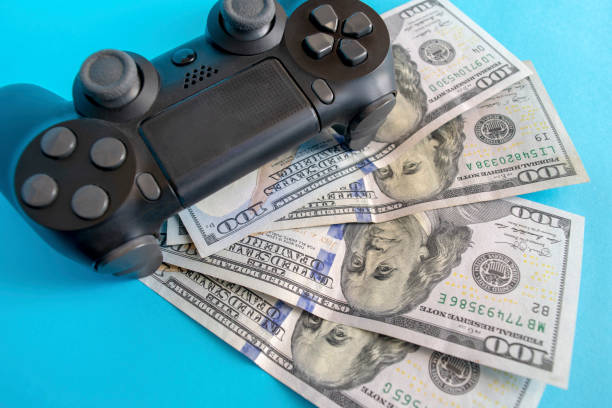 Black game joystick with us dollars on blue background stock photo