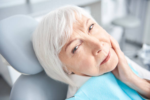 istock Senior lady experiencing a toothache at dentist room 1183945431