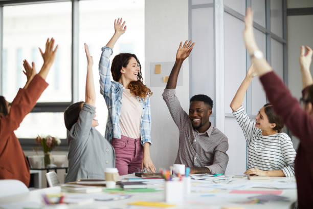 istock Joyful Creative Team Raising Hands in Meeting 1183945667