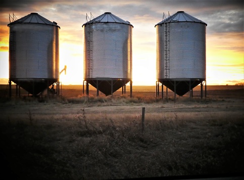 Three Grain Bins With a Sunset Background