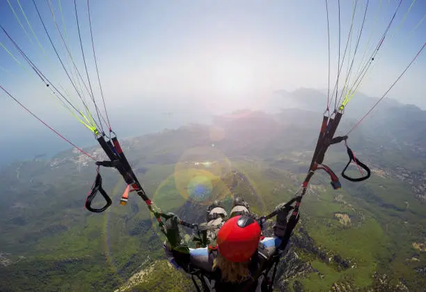 Paragliding in the sky. Woman girl is soaring in the sky on paraplane above mountains ans sea