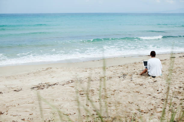 istock Young woman using laptop on a beach 1183948889