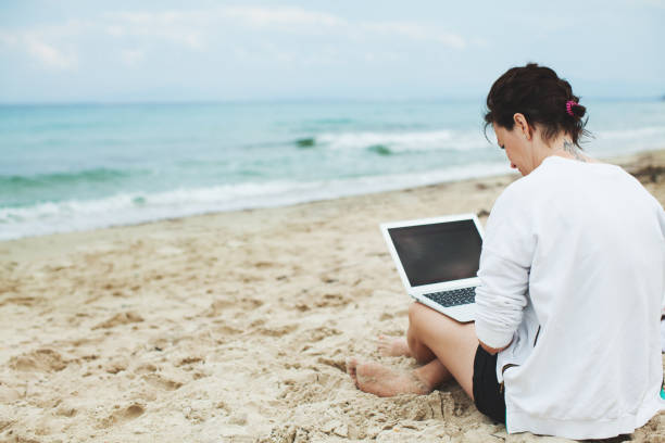istock Young woman using laptop on a beach 1183948914