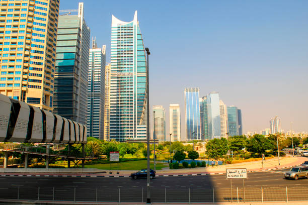 Dubai / UAE - October 15, 2019: Jumeirah Lakes Towers buildings and park. JLT road with pedestrian bridge.