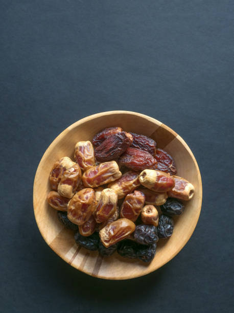istock Dates in a wooden bowl on a black background. 1183950099