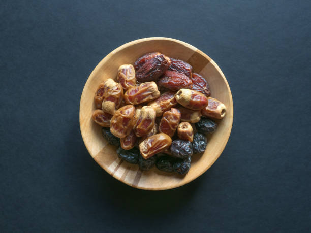 istock Dates in a wooden bowl on a black background. 1183950340