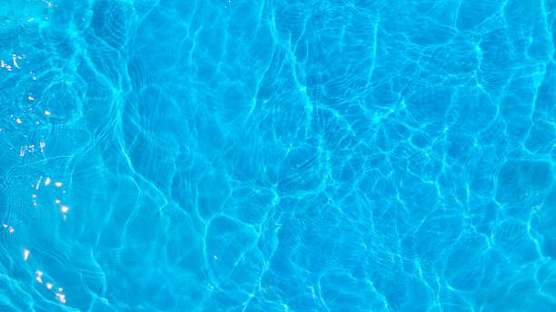 スイミングプールの青い波紋水。青いテクスチャの背景の水の表面。夏休みのためのトップビューとコピースペース。