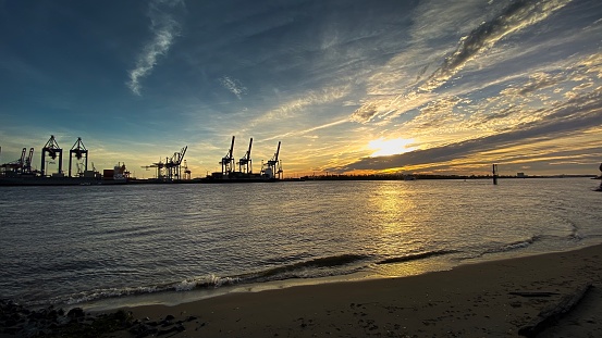 Sunset on the Elbe river with gantry cranes in the background