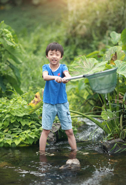 istock Child playing by a stream fishing 1183954094