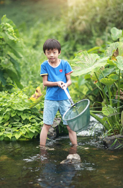 istock Child playing by a stream fishing 1183954259