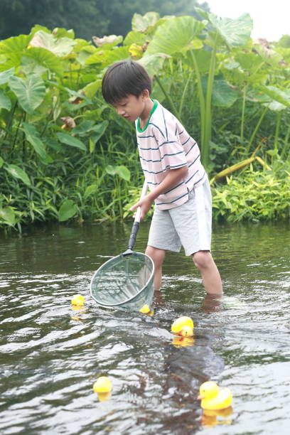 istock Child playing by a stream fishing 1183954699