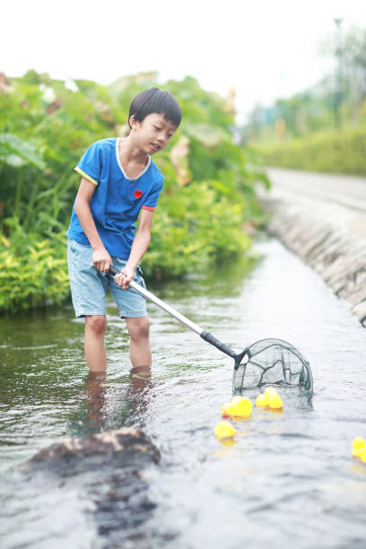 istock Child playing by a stream fishing 1183954753