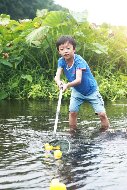 istock Child playing by a stream fishing 1183954976