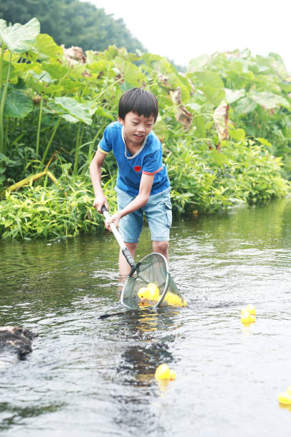 istock Child playing by a stream fishing 1183955066