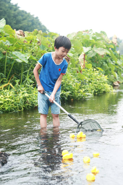 istock Child playing by a stream fishing 1183955072