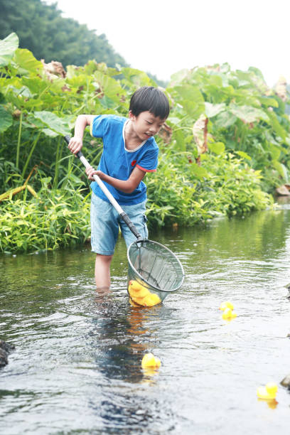 istock Child playing by a stream fishing 1183955076