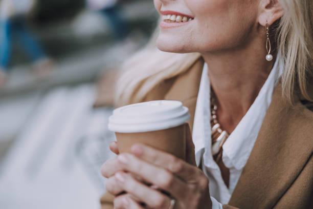 istock Smiling lady is holding hot drink on the street 1183955821