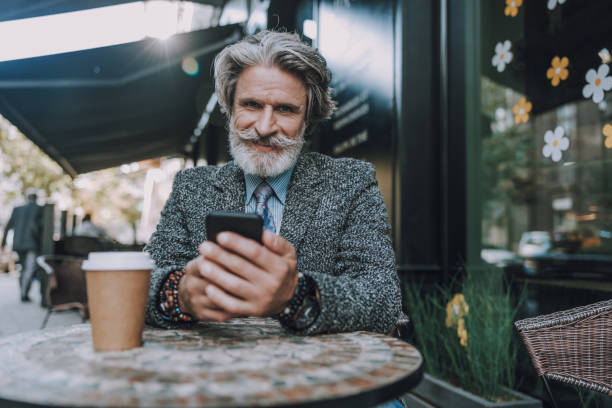 istock Smiling adult man is looking on smartphone 1183955948