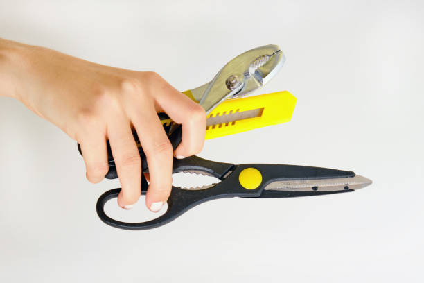 istock Scissors, pliers and a knife for cutting paper in hand. Construction tools on white background 1183956646