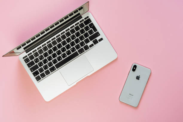 KYIV, UKRAINE - FEBRUARY 27 2019: Macbook Air and iPhone X Workplace Pink Background Top View. Smart phone on Minimal Office Desk Space. Blank Hipster Designer Workplace with Copy Space Flat Lay
