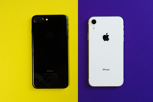 KYIV, UKRAINE - FEBRUARY 27 2019: iPhone Xr and iPhone 8 Smartphone on Yellow Purple Background Flat Lay. Black and White Mobile Phone Compare Mockup Isolated Above Top View Copy Space Bright Banner