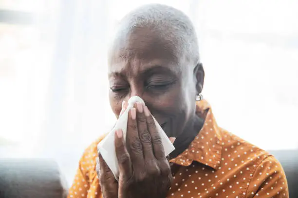 Senior Black woman holding a tissue, wiping her nose