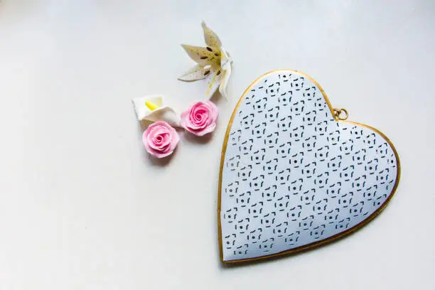 White-gold heart pendant and flowers with sugar on the background