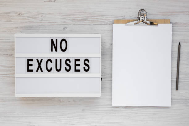 istock 'No excuses' words on a lightbox on a white wooden surface, top view. Overhead, from above, flat lay. 1183958801