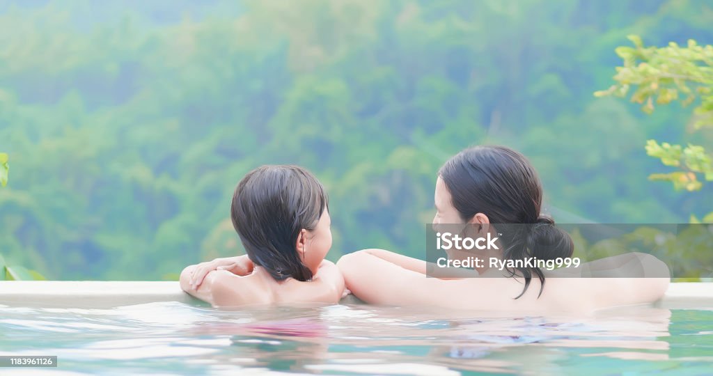 asian family enjoy hot spring rear view of asian mother and daughter enjoy outdoor hot spring Hot Spring Stock Photo