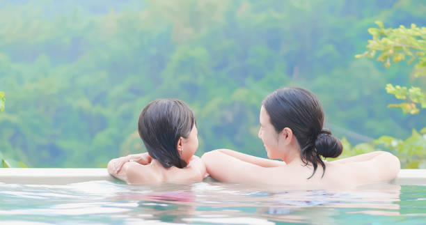 asian family enjoy hot spring rear view of asian mother and daughter enjoy outdoor hot spring taking a bath photos stock pictures, royalty-free photos & images