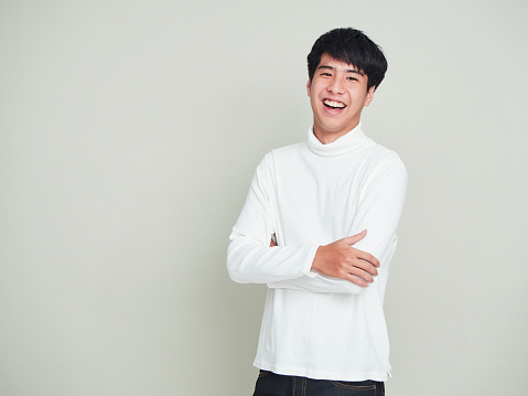Portrait of a handsome young man smiling cheerful and wearing white sweater on white background.