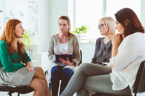 istock Woman discussing with group during therapy session 1183961323