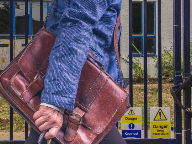 Businesswomen with leather briefcase walking along a city street A man with a leather briefcase and a blue jacket walking along the warning signs. uncompromising stock pictures, royalty-free photos & images